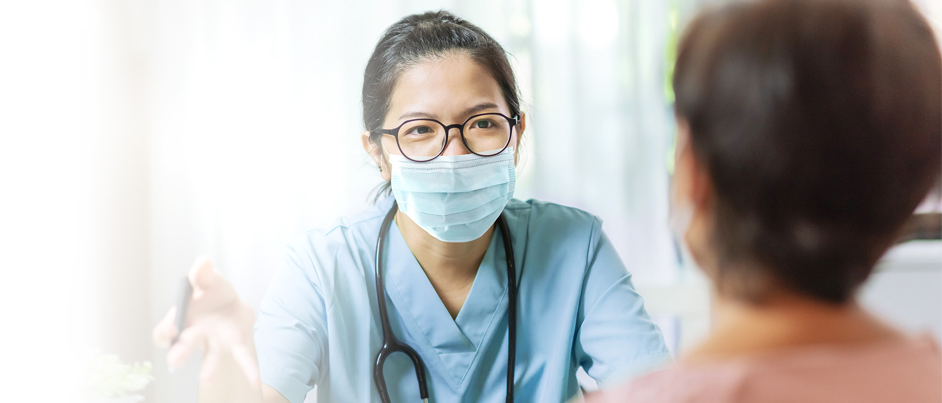 Asian Doctor or nurse in blue uniform concentrate working on laptop computer and preparing information of patients for meeting with medical team in hospital. Selective focus on hand